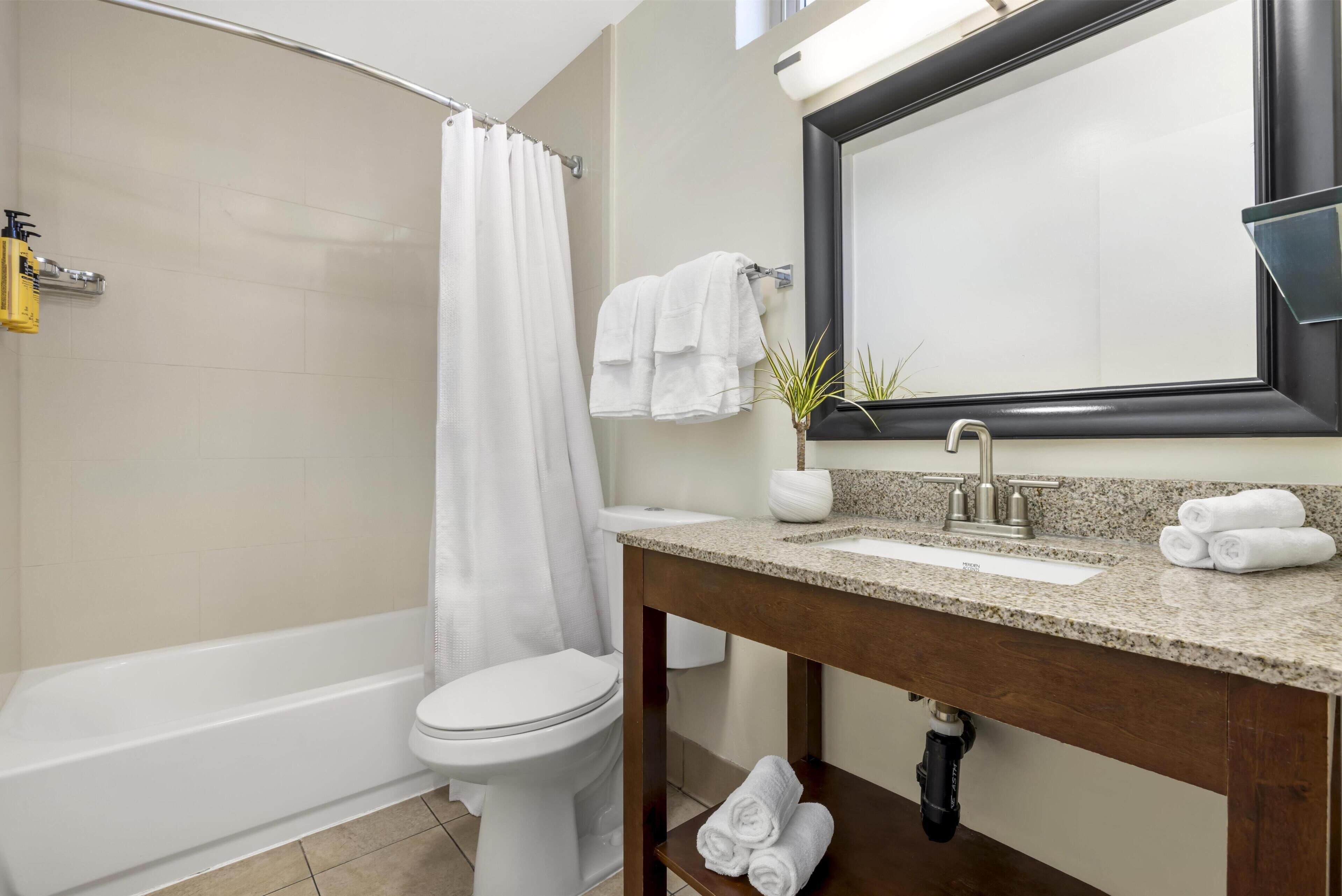 A modern bathroom with a bathtub, toilet, and vanity with a mirror.