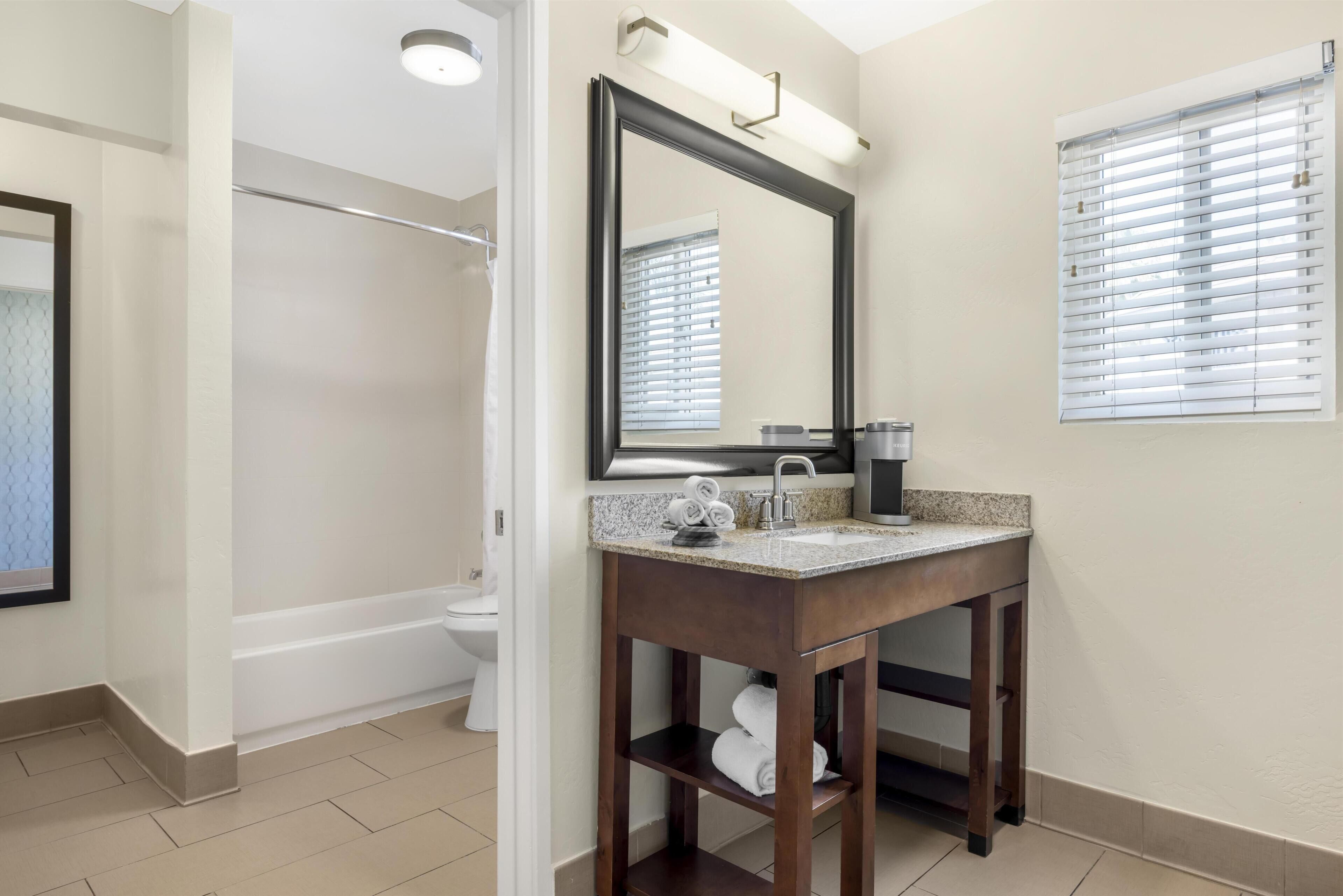 Une salle de bain équipée d’un lavabo, d’un miroir, d’un porte-serviettes et d’un espace douche.