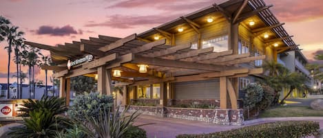 A modern hotel with a covered patio, landscaped garden, and a clear view of the surrounding area.