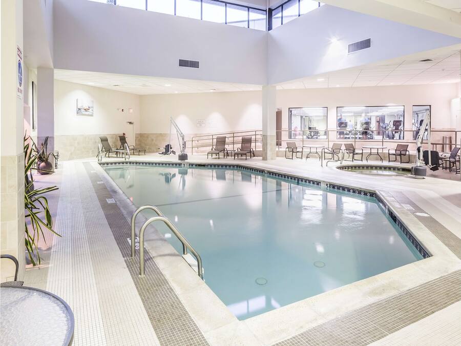 Una piscina interior con agua cristalina, rodeada de sillones de descanso y mesas.