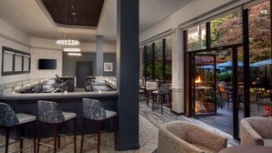 A modern bar area with a counter, bar stools, and a seating area with a round table and chairs.