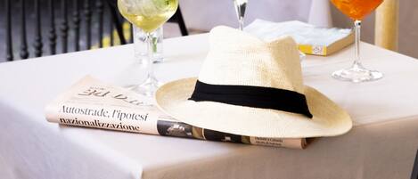 A table with two drinks, a hat, and a book.
