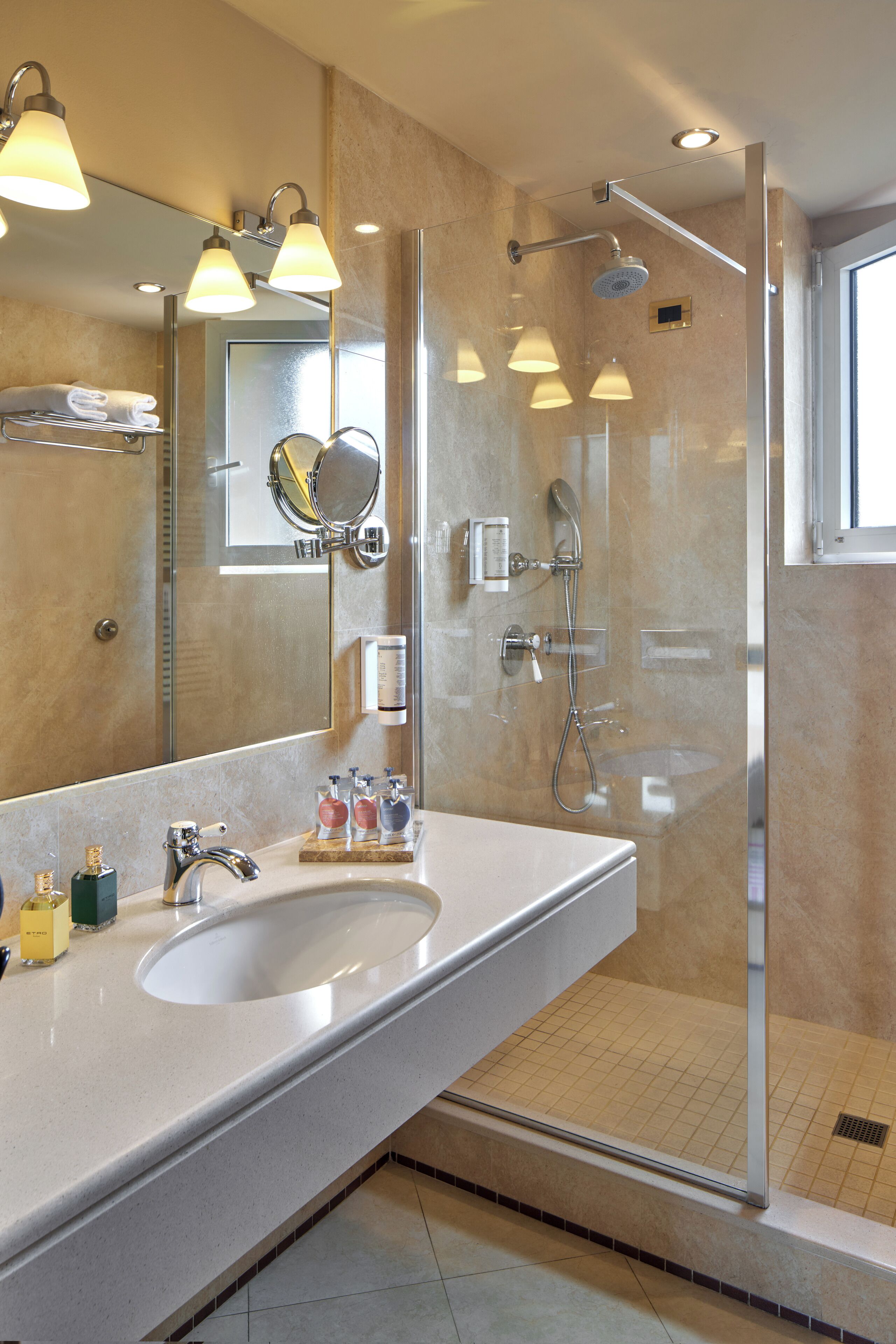 A modern bathroom with a large sink, mirror, and glass-enclosed shower.