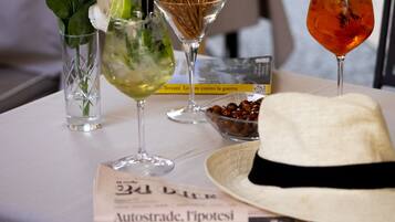 A table with three drinks, a white hat, and a book titled "Autostrade, Pipotez".