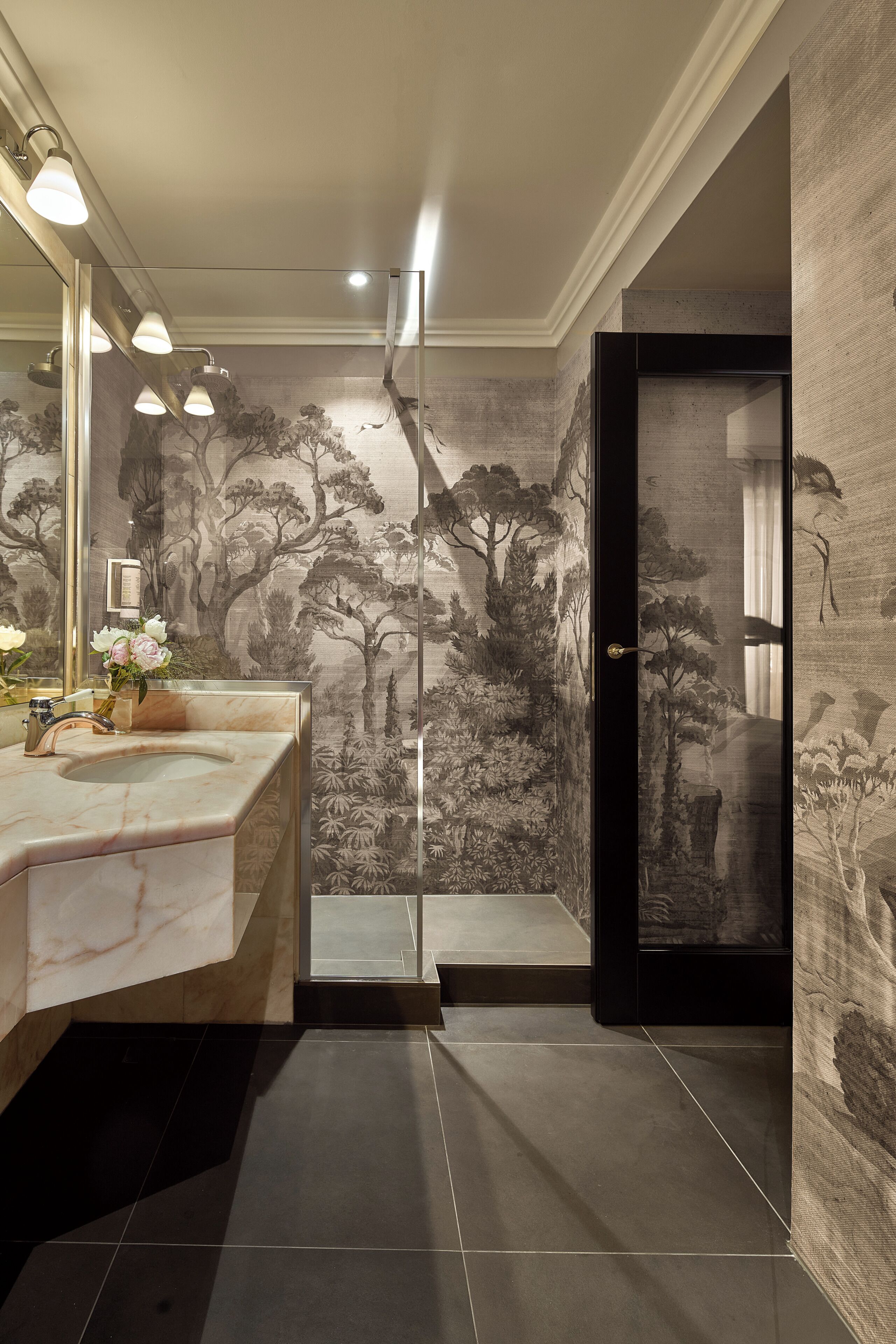 A bathroom with a marble sink, a large mirror, and a wall with a nature-themed mural.