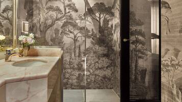 A bathroom with a marble sink, a large mirror, and a wall with a nature-themed mural.