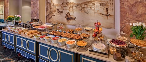 A buffet with various food items and a mural of a cityscape.