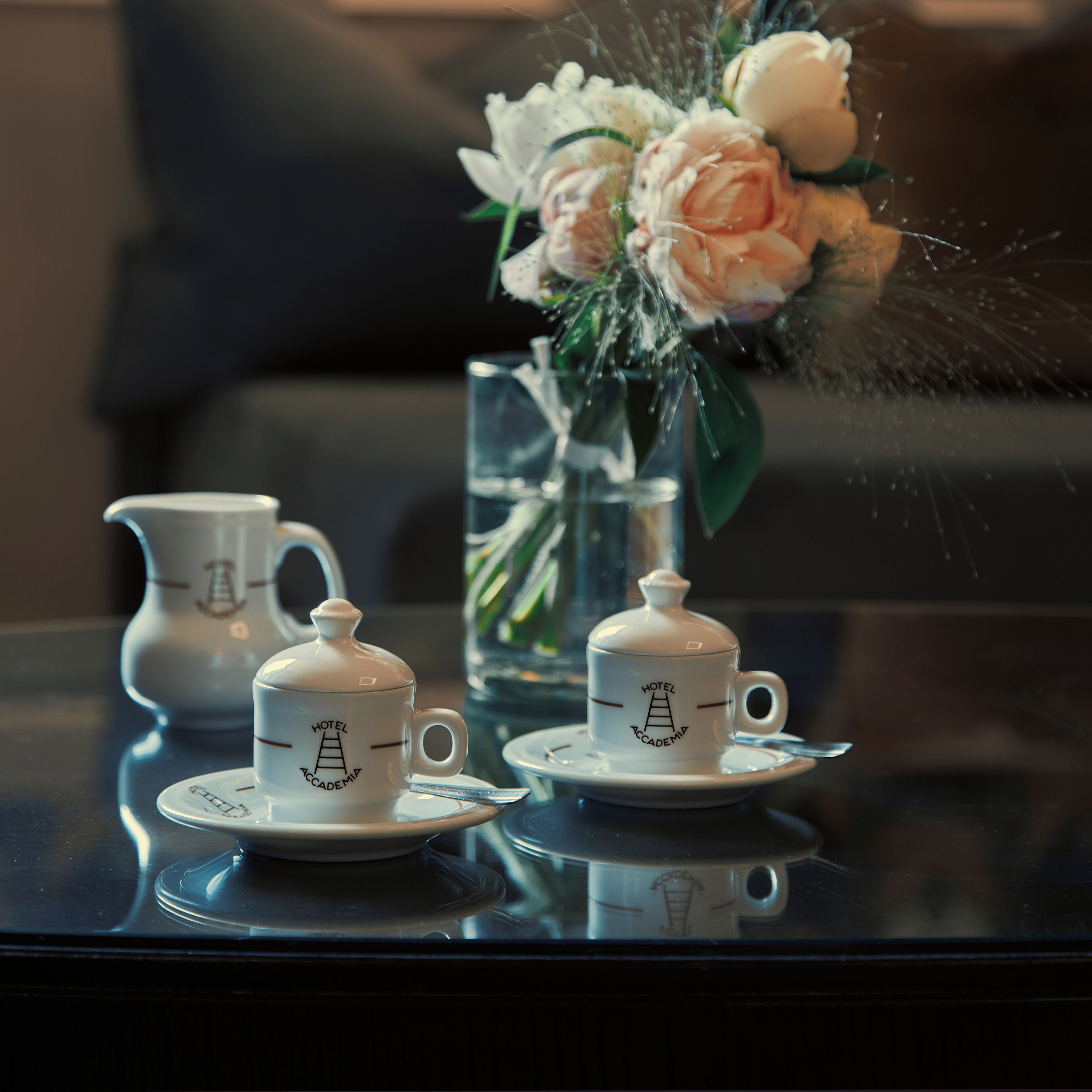 A table with a tea set and a vase with flowers.