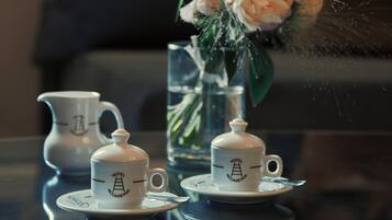 A table with a tea set and a vase with flowers.