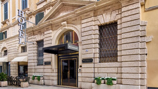 A historic building with a classical facade, a central entrance with a black awning, and a sign indicating a restaurant. - Hotel Accademia (Verona)