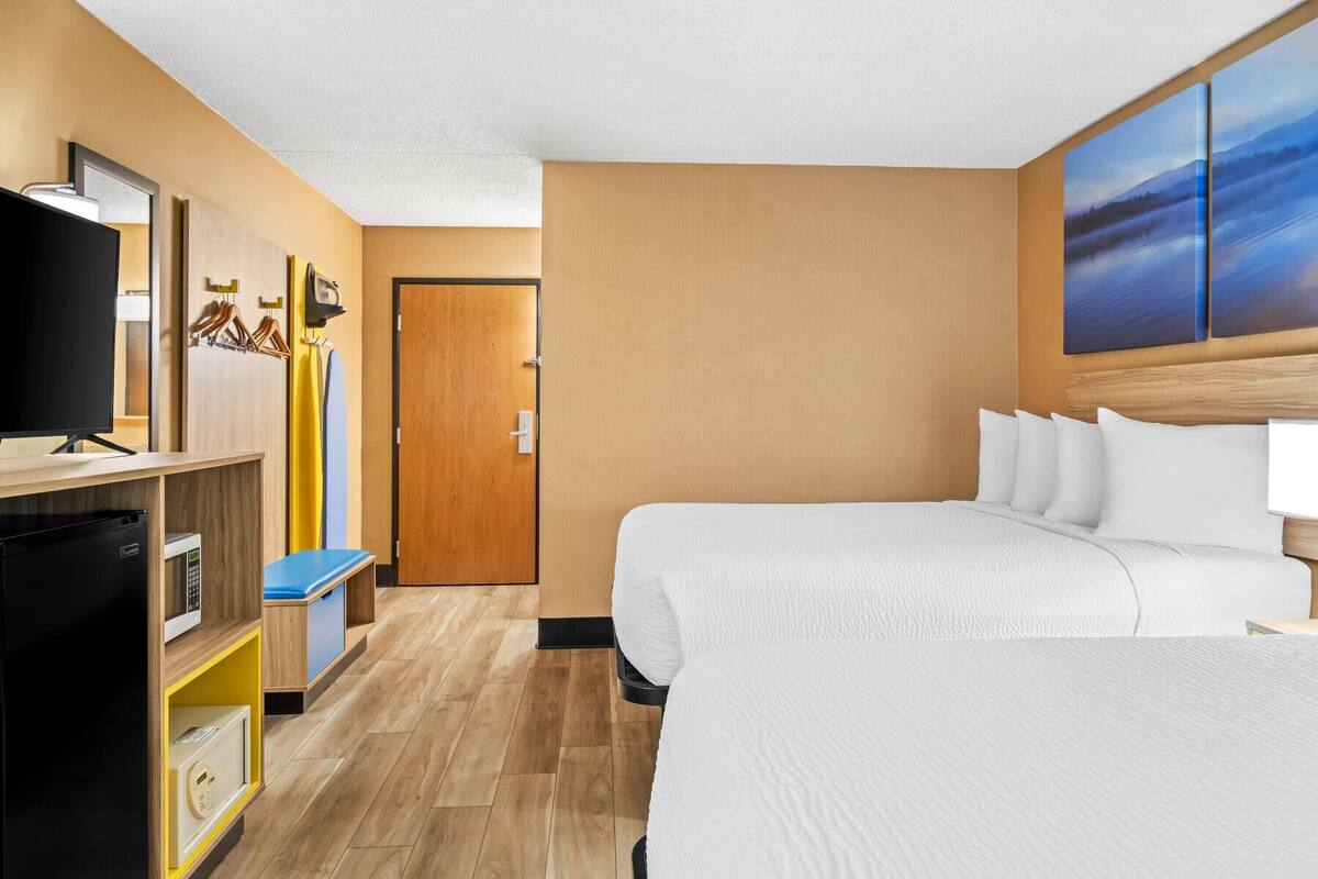 Ein Hotelzimmer mit Bett, Fernseher, Mikrowelle und einem Holzschrank.