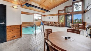 A pool area with a wooden ceiling, a table with chairs, and a view of the outside. - Days Inn by Wyndham Helena (Helena)