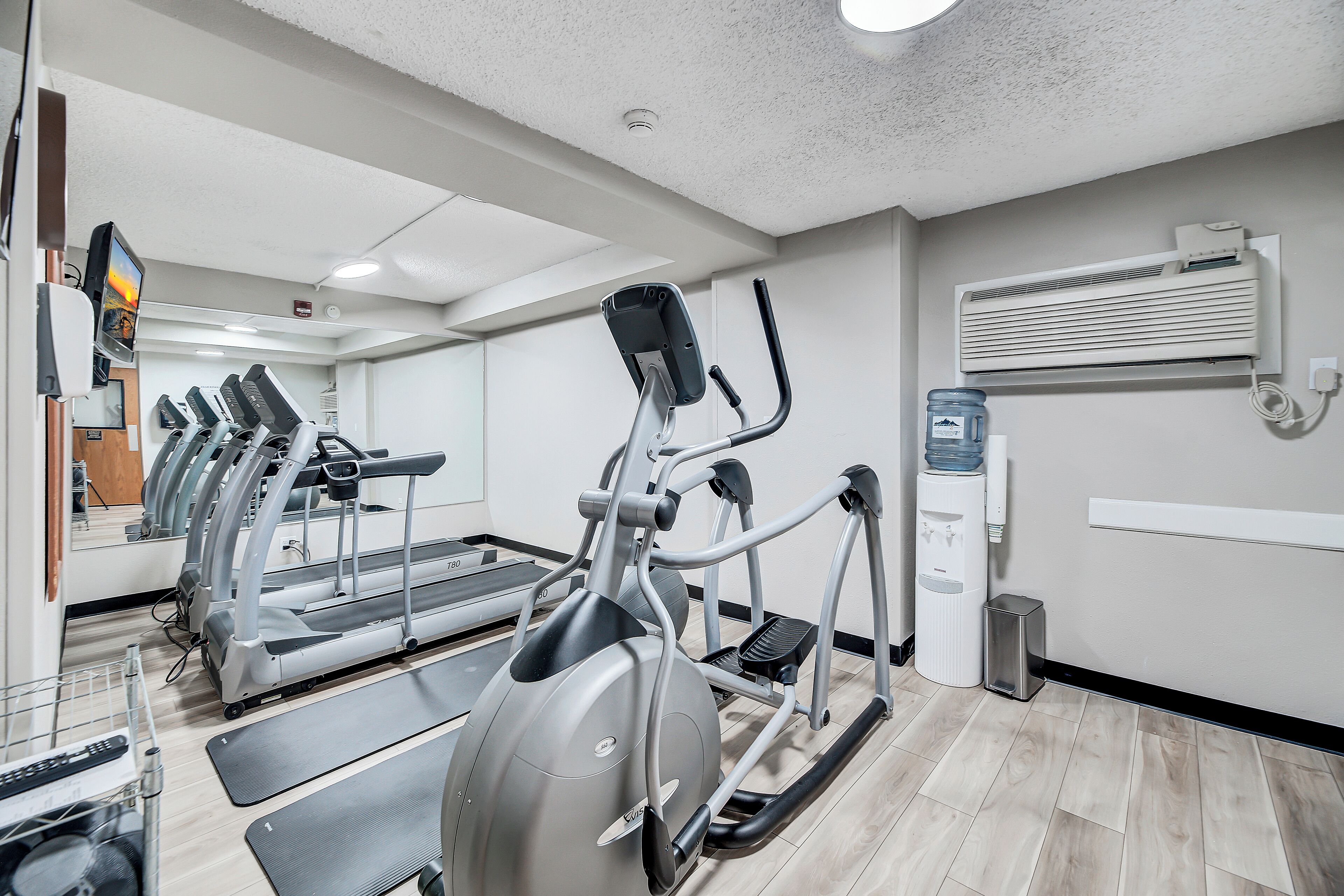 A gym with treadmills, elliptical machines, and a water dispenser.