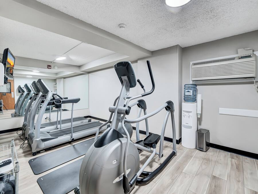 A gym with treadmills, elliptical machines, and a water dispenser.