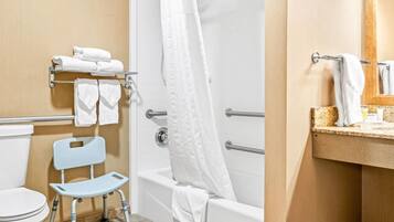 A bathroom with a toilet, a shower with a glass door, a grab bar, a towel rack, and a sink with a mirror.