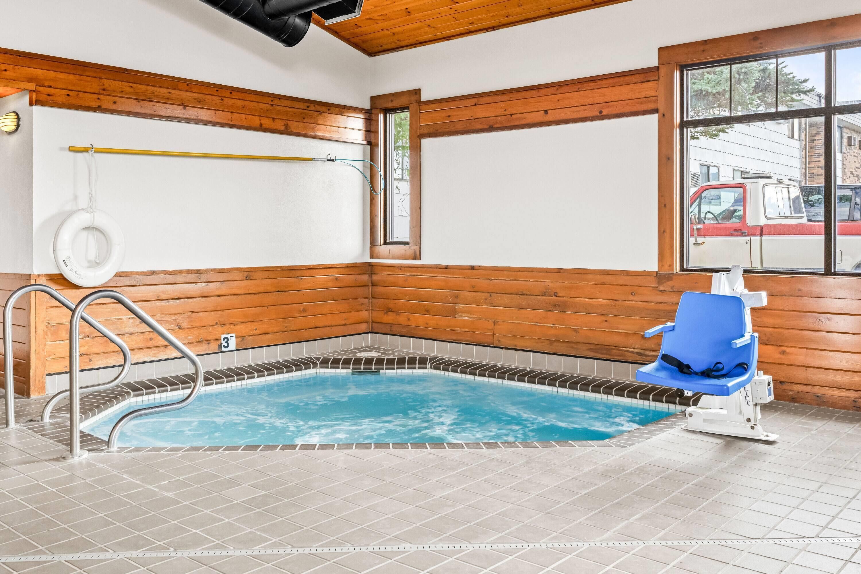 A small indoor pool with a blue water feature, wooden walls, and a blue chair.