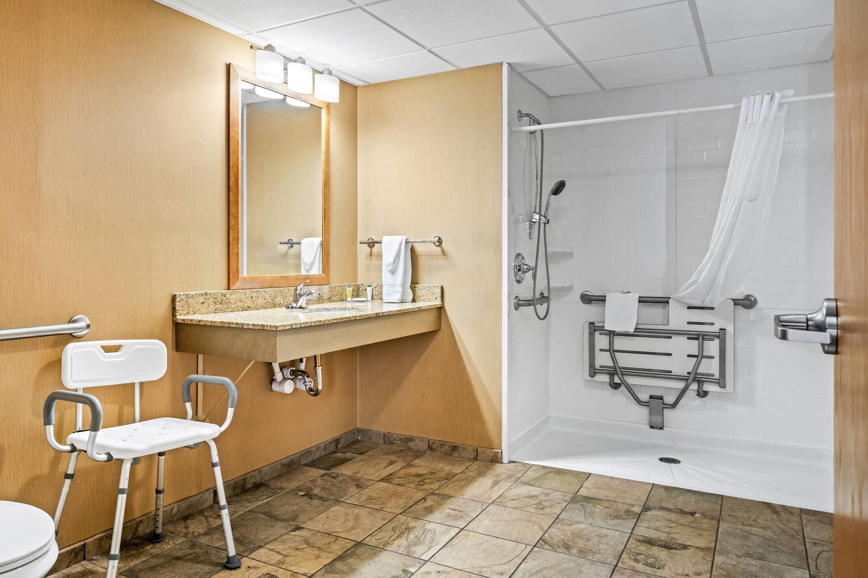 Une salle de bain avec une douche, des toilettes et une chaise.