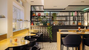 Et moderne restaurantmiljø med barområde, sorte stole og flisegulv.
