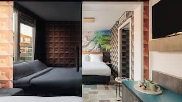 A hotel room with a bed, a sofa, a small table with a tray, and a view of a cityscape through a window.