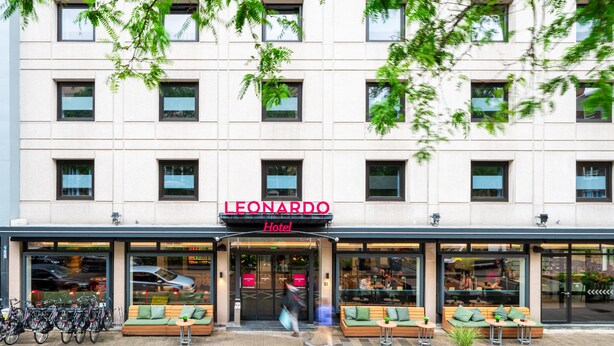 Et hotel med moderne facade, udeservering og cykler parkeret udenfor.