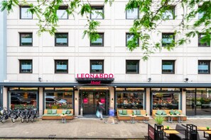 A hotel with a modern facade, outdoor seating area, and bicycles parked outside. - Leonardo Hotel Rotterdam Savoy (Rotterdam)