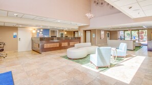 A hotel lobby with a reception desk, seating area, and a large window providing a view of the outdoors. - Holiday Inn Express Richmond - Midlothian Turnpike by IHG (Richmond)