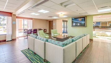 Um saguão de hotel com área de estar, balcão de recepção e televisão.