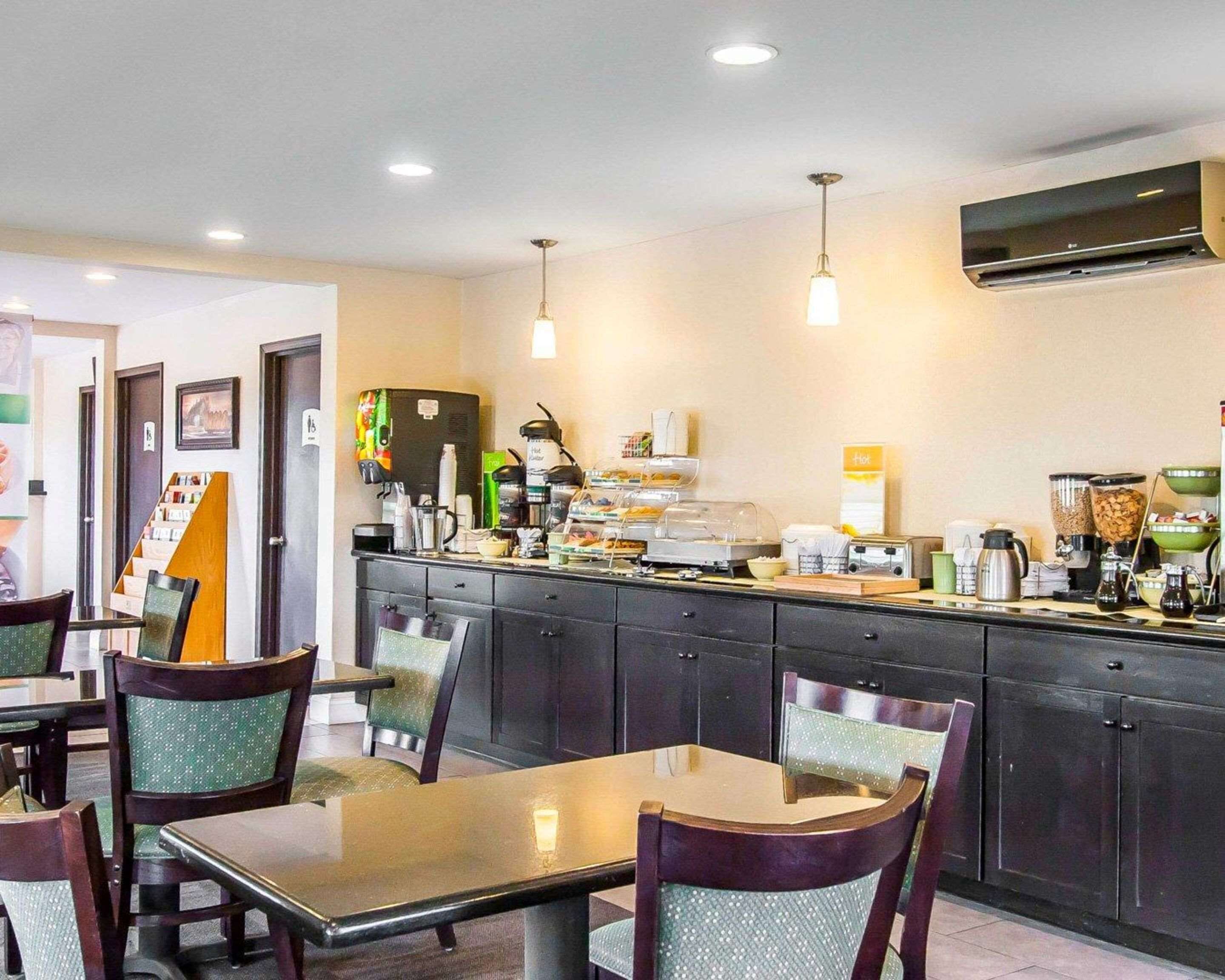 A hotel dining area with a counter, chairs, and various food and beverage dispensers.