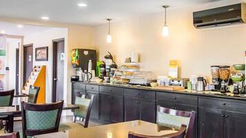 A hotel dining area with a counter, chairs, and various food and beverage dispensers.