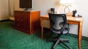 A hotel room with a desk, chair, television, and a lamp. - Quality Inn Cairo I-57 (Cairo)