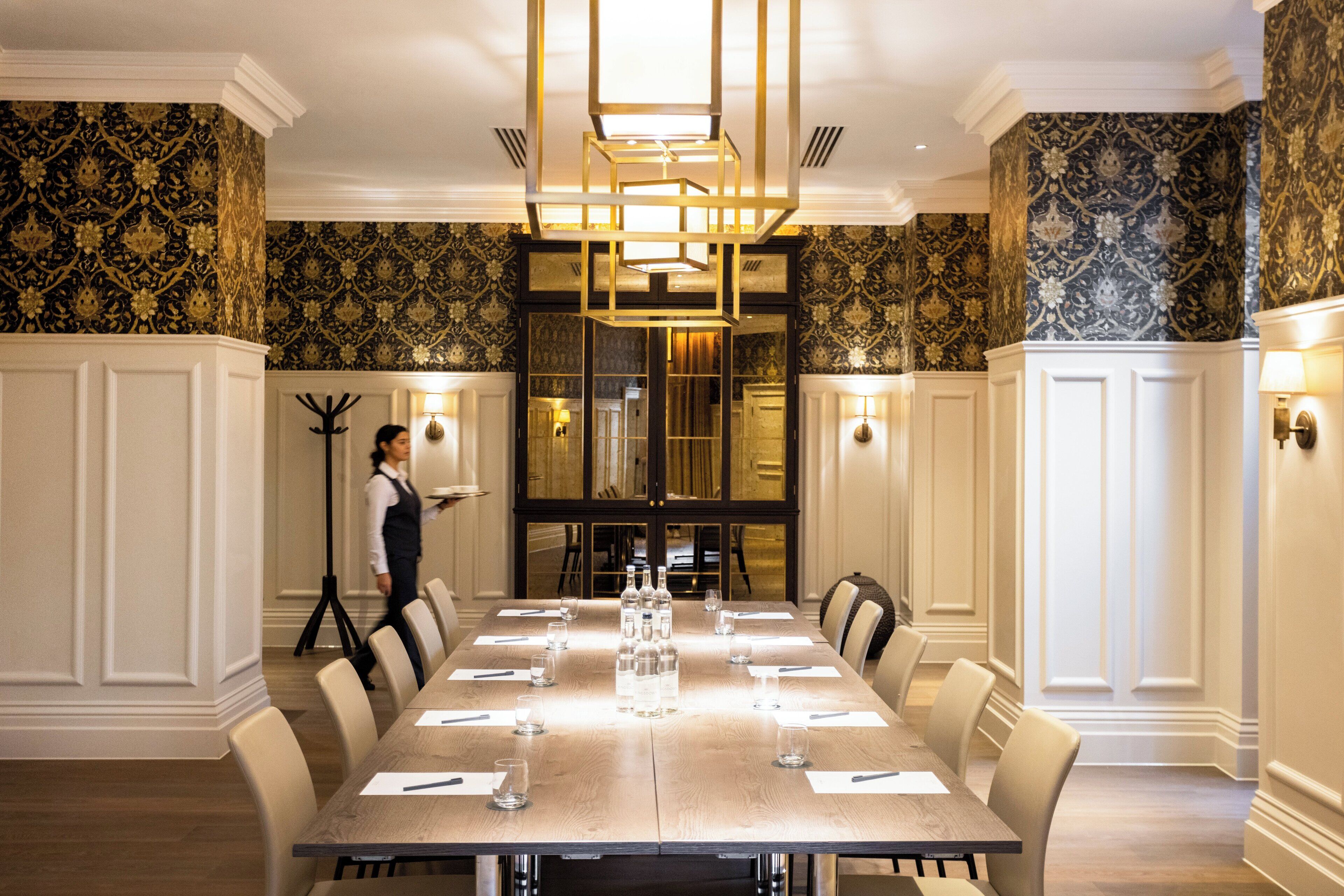 A formal dining room with a long table set for a meal, surrounded by chairs.