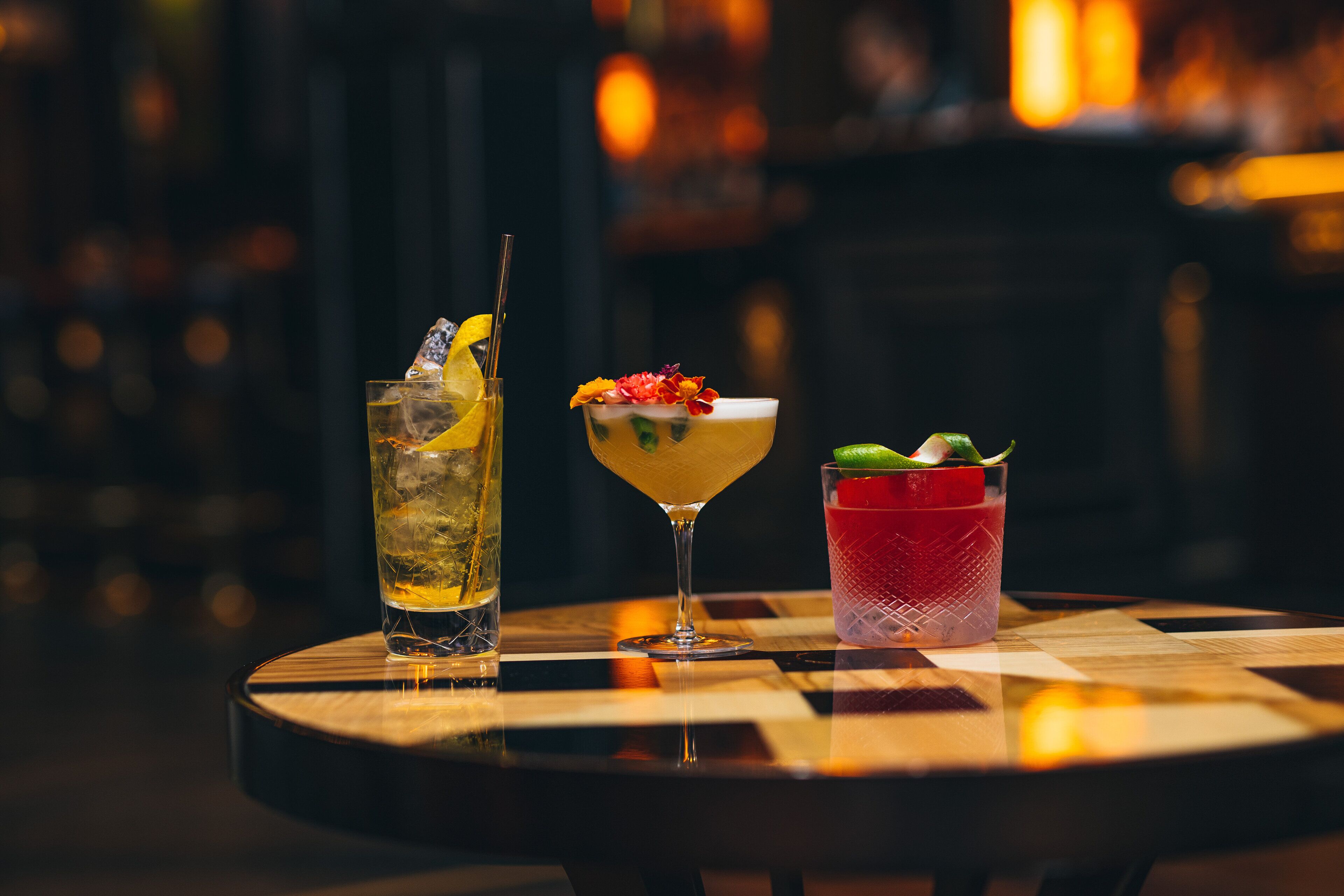 Tres bebidas sobre una mesa redonda con un mantel a cuadros.