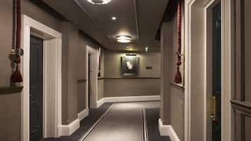 A hallway with carpeted floors, white walls, and doors with brass handles.