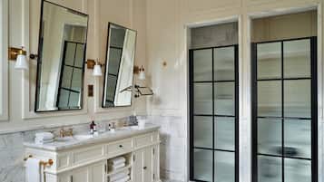 A bathroom with a marble vanity, two large mirrors, and a glass shower enclosure.