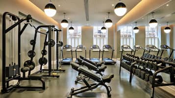 Een fitnessruimte met loopbanden, krachttoestellen en gewichten.