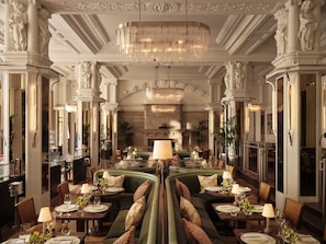 A grand dining hall with a central seating arrangement, ornate columns, and a large chandelier. - Kimpton Fitzroy London by IHG (London)