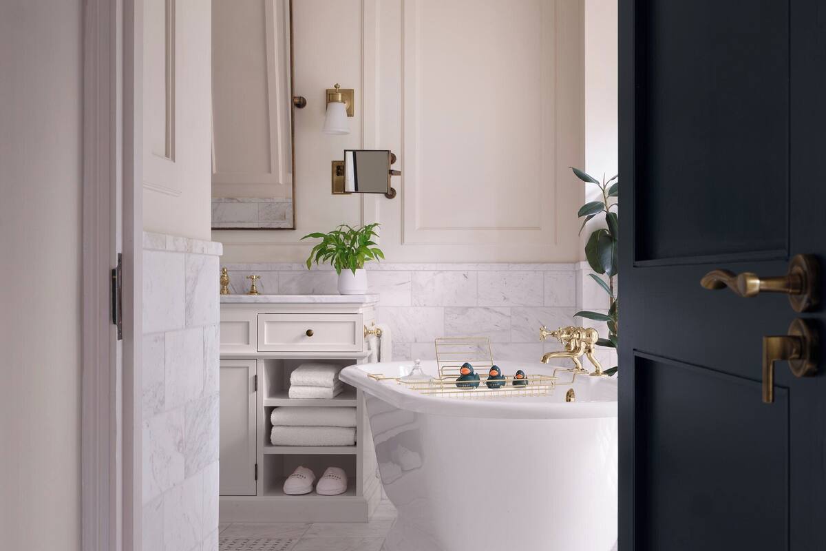 A modern bathroom with a freestanding bathtub, a vanity with a mirror, and a potted plant.