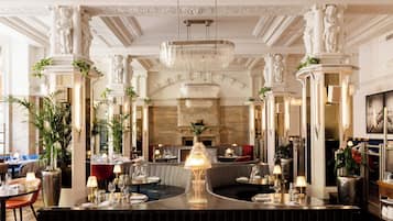 A luxurious hotel lobby with a central bar, seating areas, and classical architectural details.