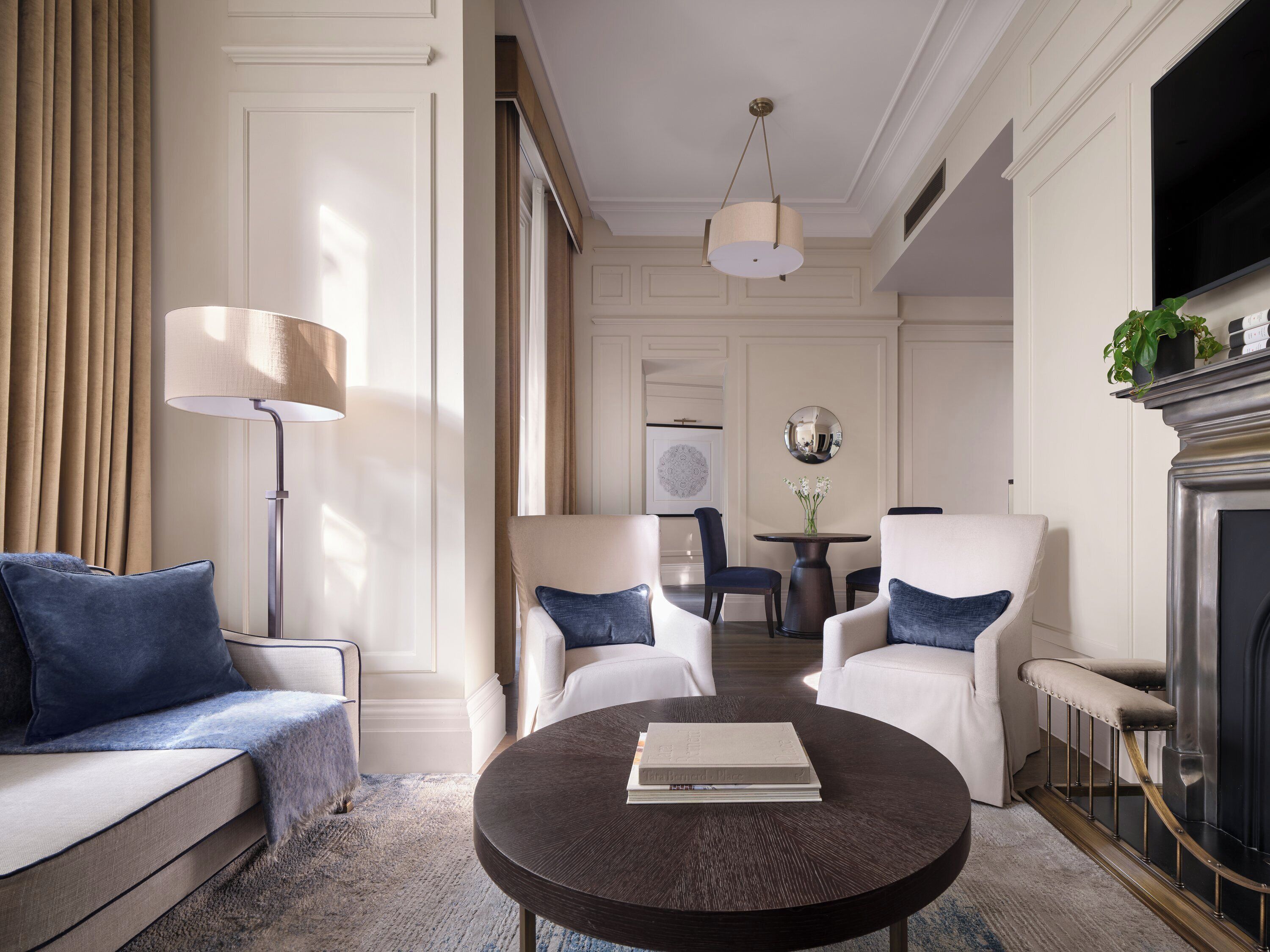 Un salon bien éclairé, avec un canapé, des fauteuils, une table basse et une cheminée.