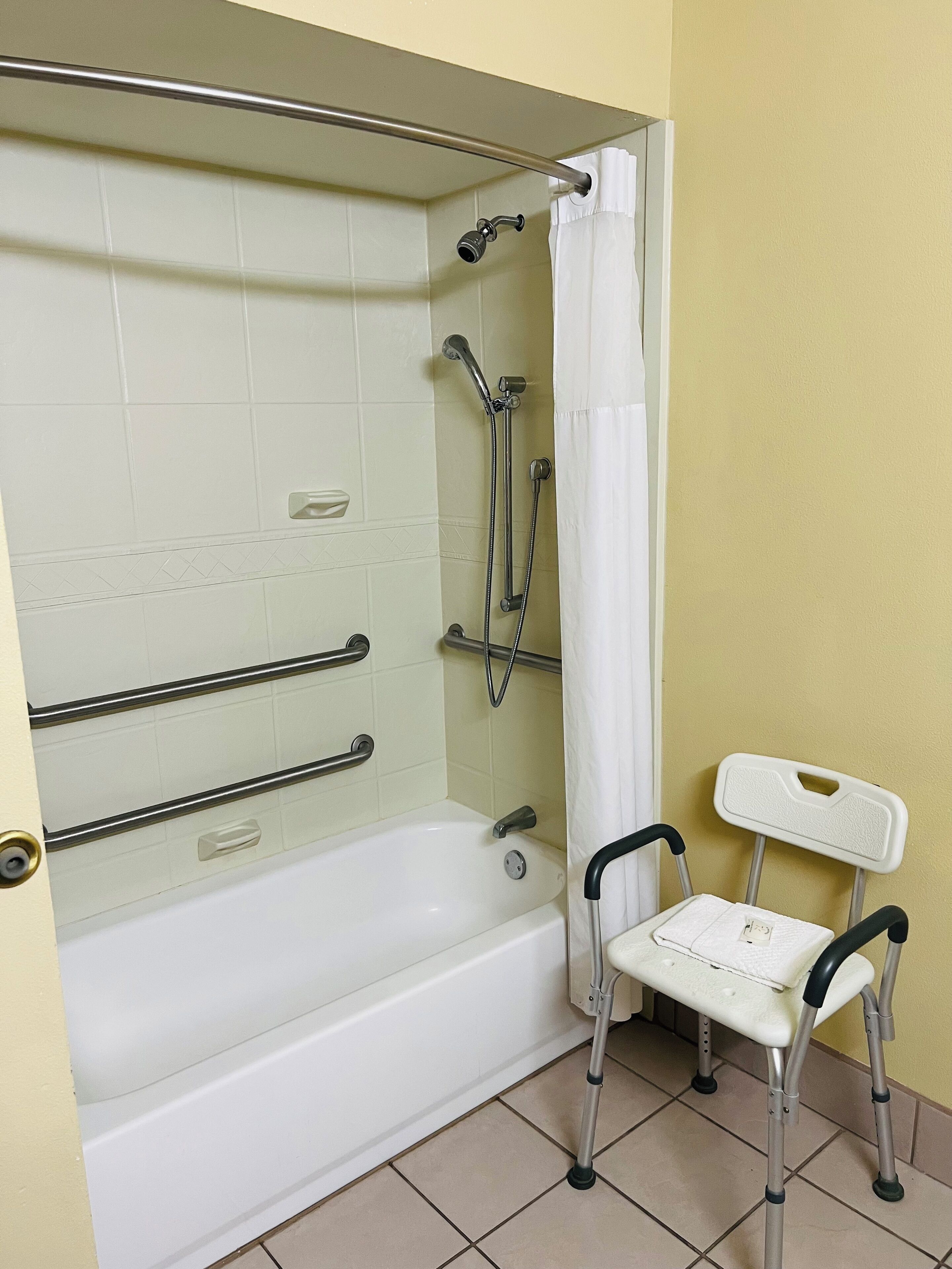 A bathroom with a bathtub, shower, and a wheelchair-accessible bench.