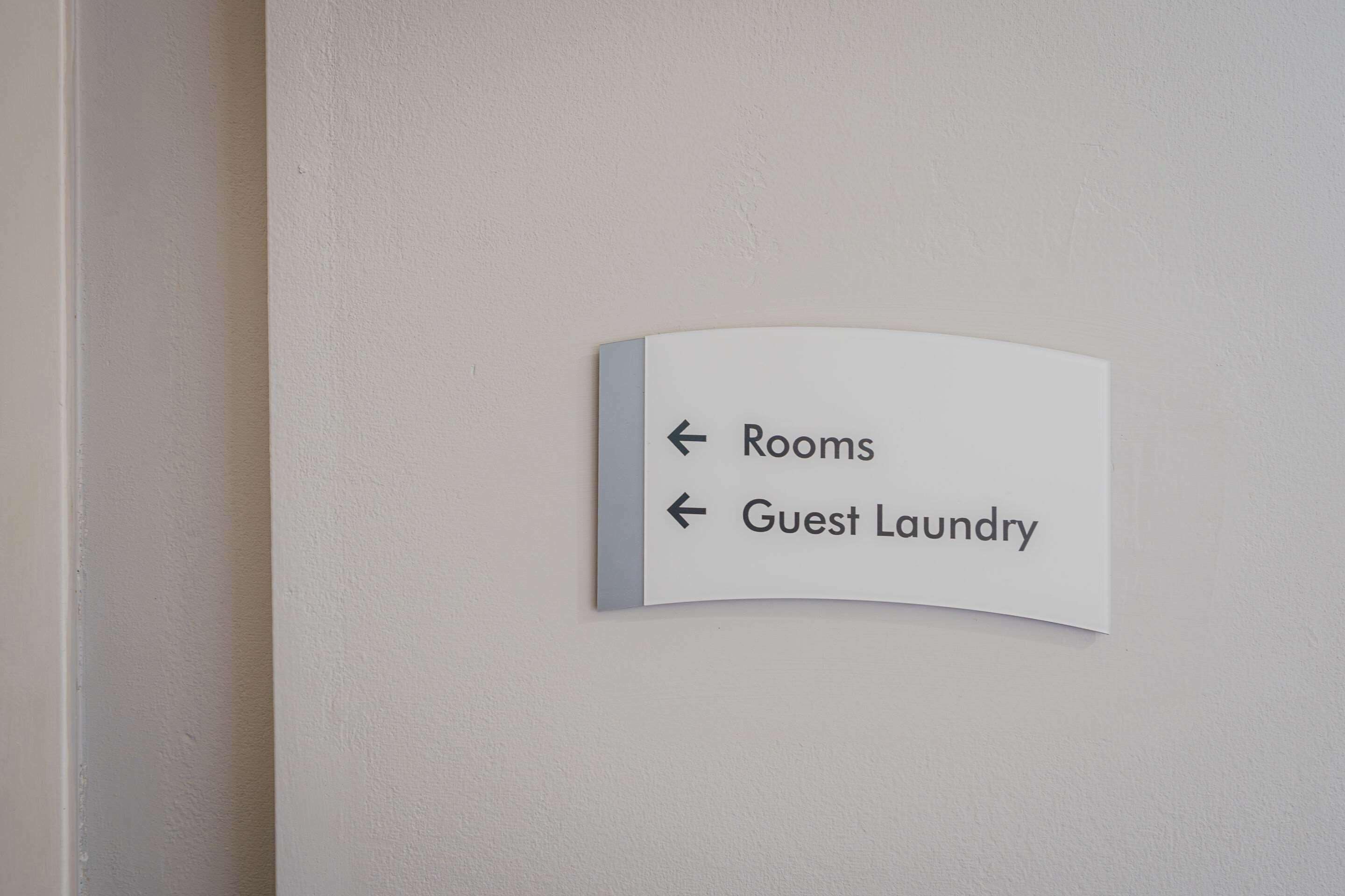 A directional sign with arrows pointing to 'Rooms' and 'Guest Laundry'.