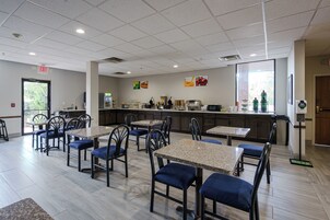 Un restaurante con varias mesas y sillas, una zona de cocina y un amplio ventanal.