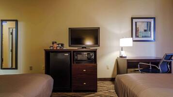 Habitación de hotel con dos camas, televisión, microondas, escritorio con lámpara y un cuadro en la pared.