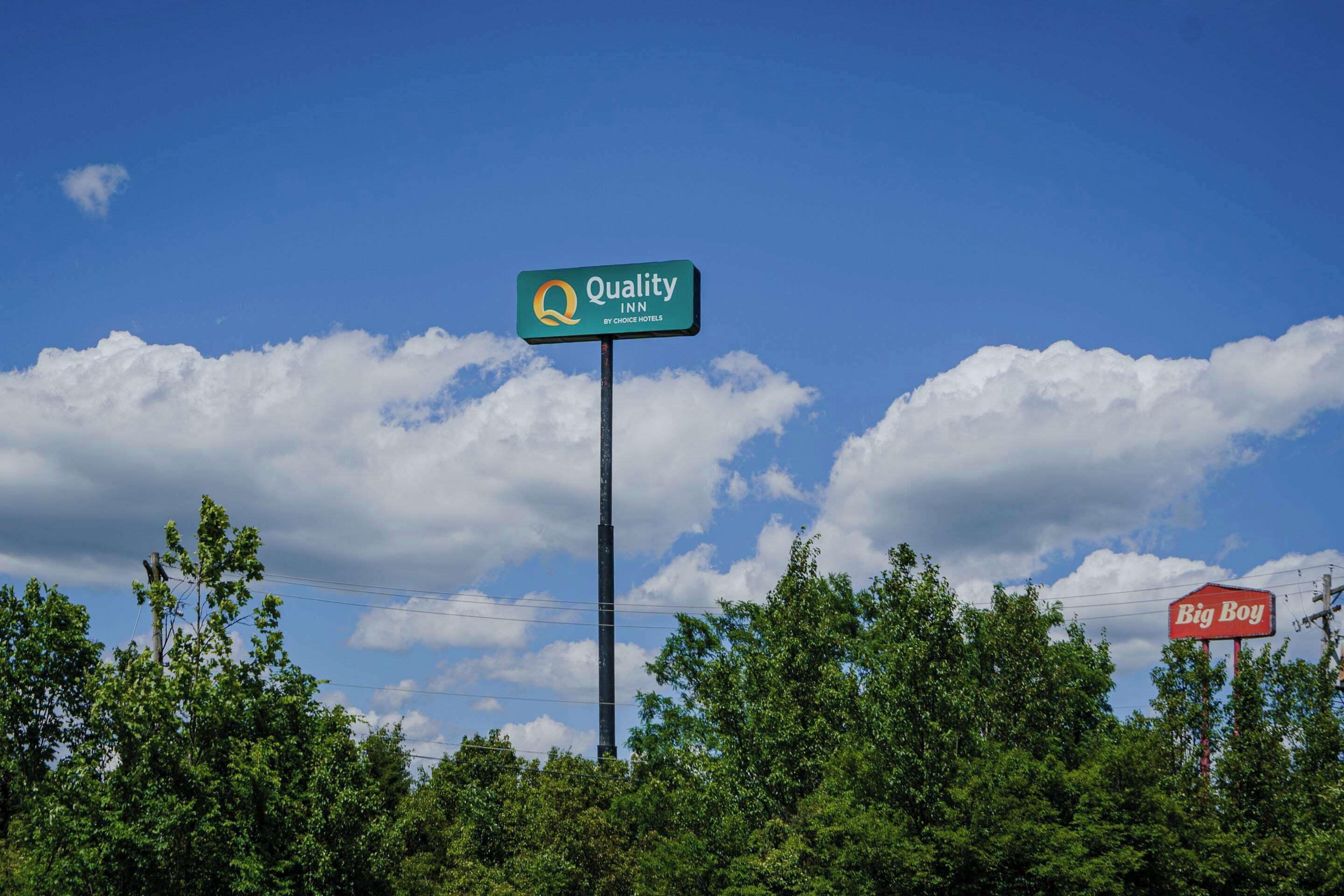 A Quality Inn sign with a clear blue sky and clouds in the background.