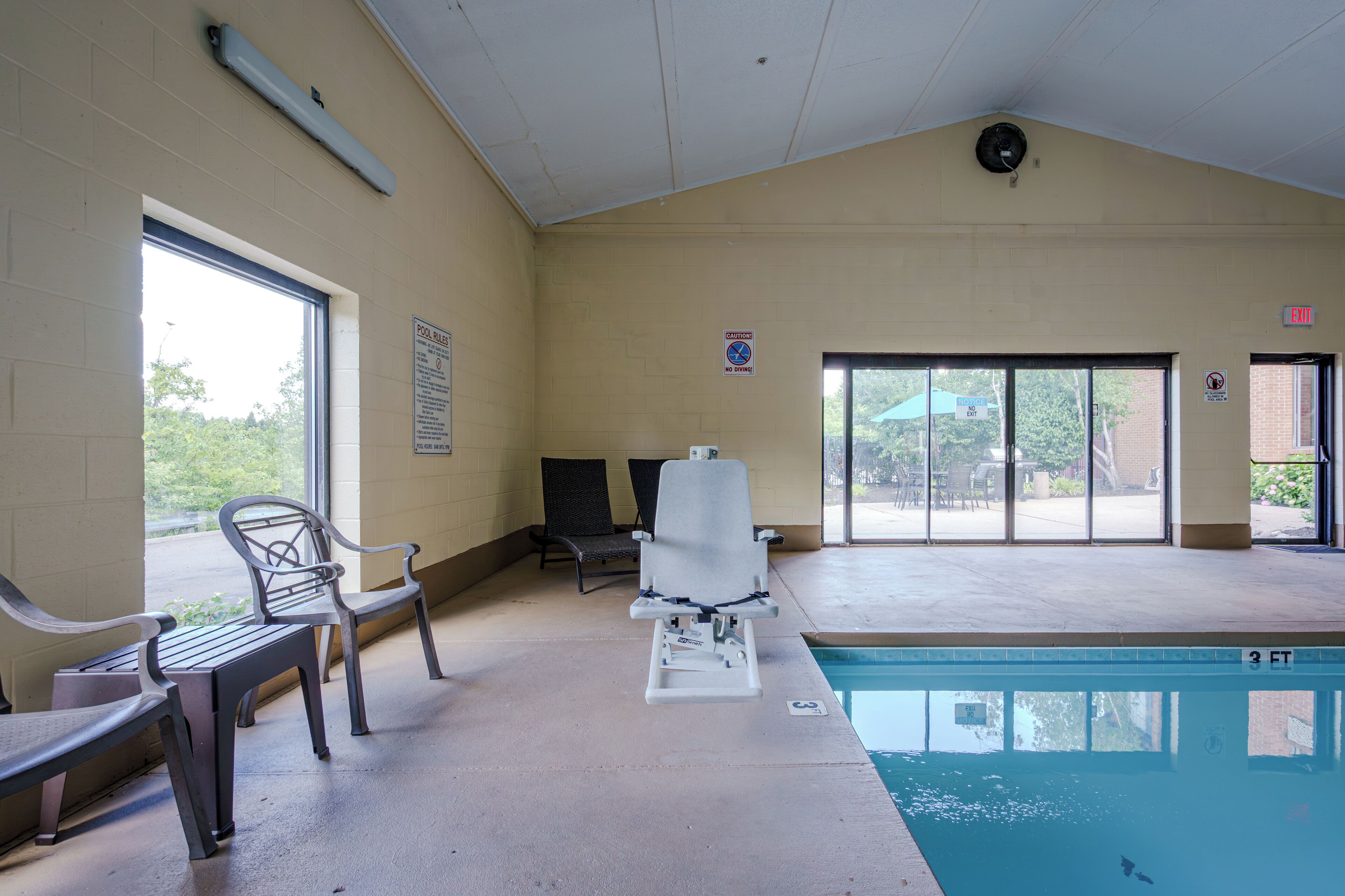 Una piscina interior con un banco, sillas y una silla para socorrista.