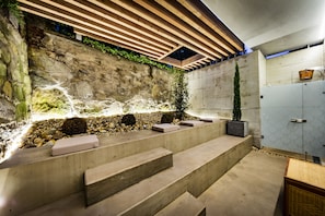 A modern interior with a stone wall, wooden beams, and a concrete staircase.