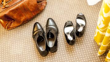 Schwarze Schuhe, eine braune Ledertasche und ein gelbes Stoffmuster.