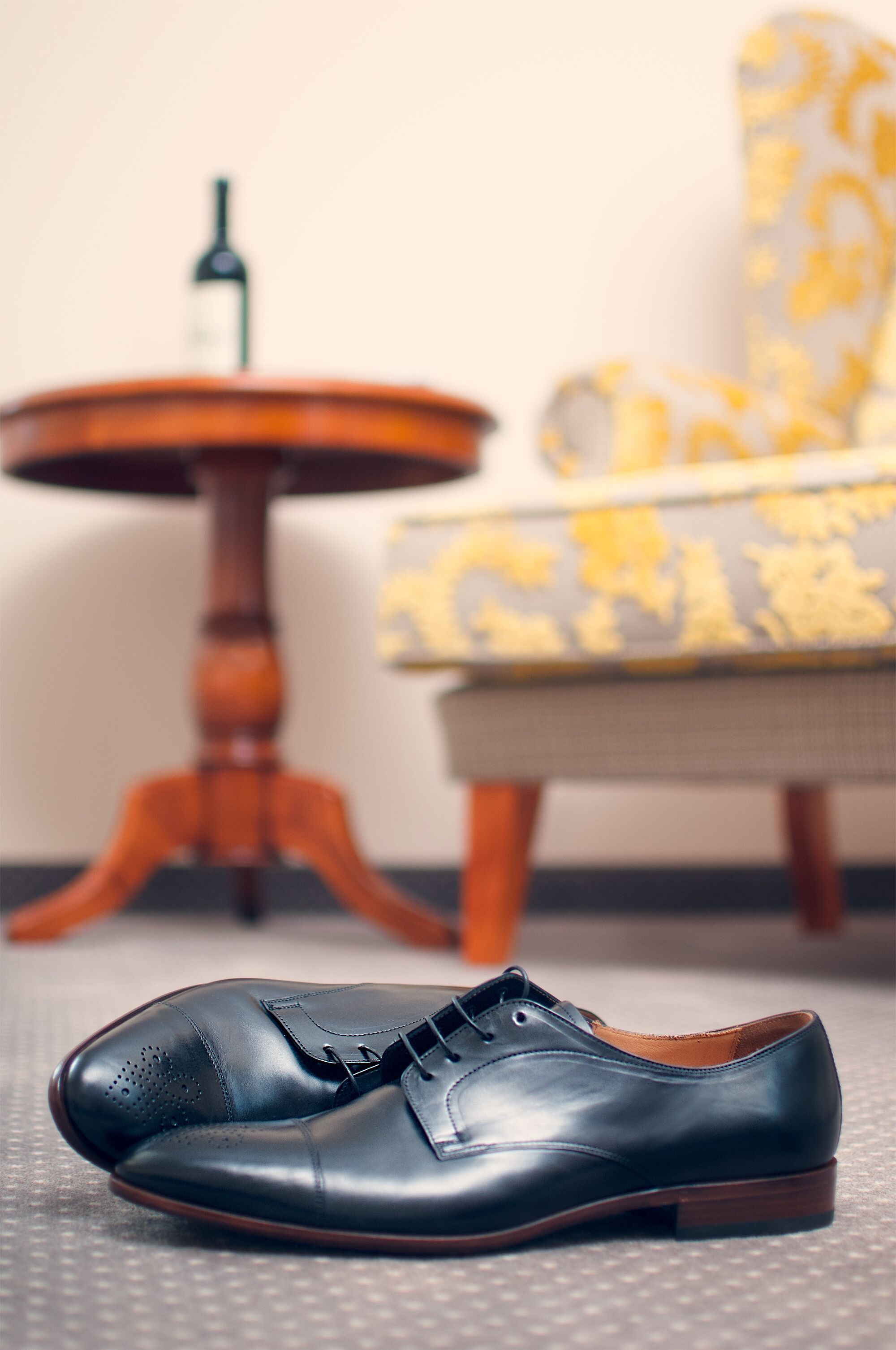 A single black leather shoe on a textured floor.