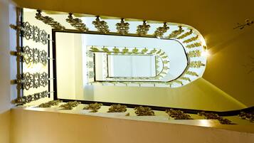 Una escalera de caracol con barandillas metálicas decorativas y un espejo que refleja la escalera.