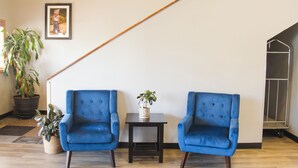 A room with two blue armchairs, a small table with a plant, a framed picture on the wall, and a wooden floor. - Quality Inn Spearfish I-90 (Spearfish)